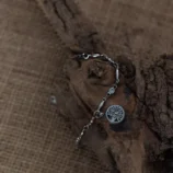 Bransoletka z symbolem Drzewa Życia w srebrnym kolorze na tle korzenia drzewa