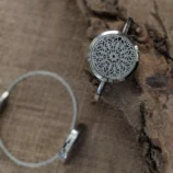 Metalowa bransoletka z dekoracyjnym wzorem na naturalnym drewnie