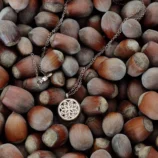 Naszyjnik z różowego złota z ażurowym wisiorem na tle orzechów laskowych