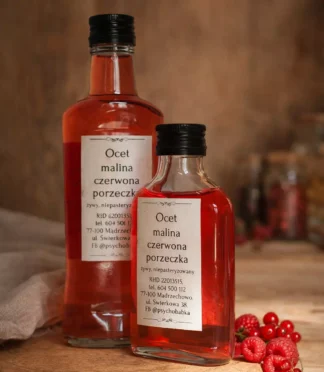 Dwie butelki octu malinowo-porzeczkowego na drewnianym blacie