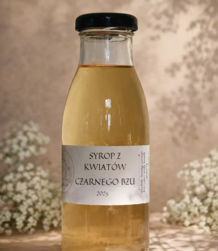 syrop z kwiatów czarnego bzu Szklana butelka z syropem z kwiatów czarnego bzu i kwiatami bzu w tle