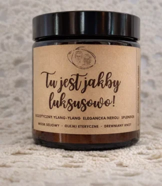 Świeca zapachowa w słoiku z napisem "Tu jest jakby luksusowo" na etykiecie