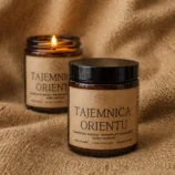 Dwie świece sojowe w szklanych, brązowych słoikach z etykietą z napisem "Tajemnica orientu".