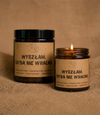 Świece sojowe w szklanych słoikach w kolorze brązowym z etykietami z napisem „Wyszłam. Chyba nie wracam.” Świece aromaterapeutyczne z olejkami eterycznymi wspierającymi relaks. Świece sojowe w szklanych słoikach w kolorze brązowym z etykietami z napisem "Wyszłam. Chyba nie wracam." stojące na jutowej tkaninie.