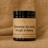 Świeca sojowa w szklanym, brązowym słoiku z etykietą z napisem "Ziewanie to cichy krzyk o kawę" o słodkim, kawowym zapachu.