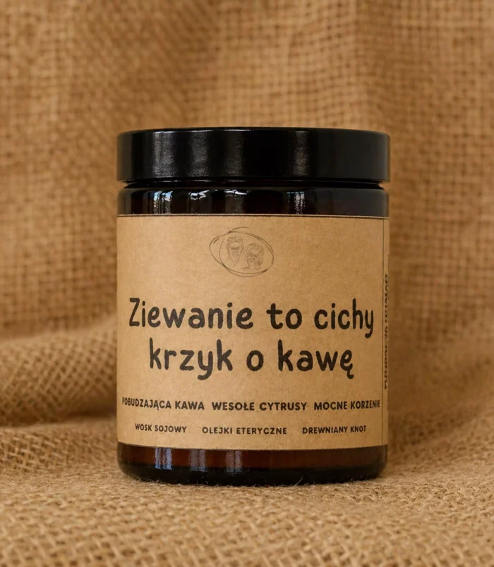 Świeca sojowa w szklanym, brązowym słoiku z etykietą z napisem "Ziewanie to cichy krzyk o kawę" o słodkim, kawowym zapachu.